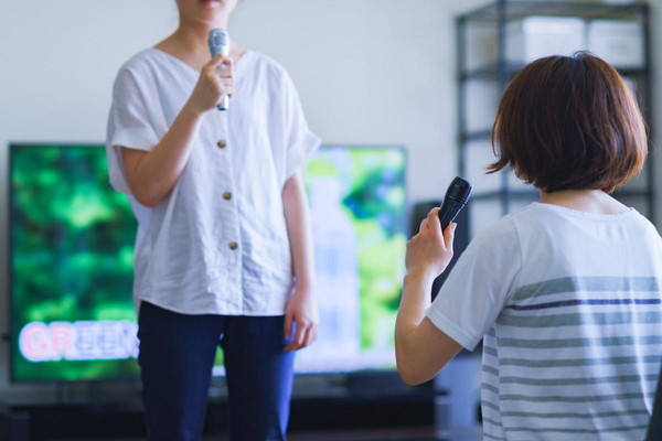 家の中でマイクで歌う女性